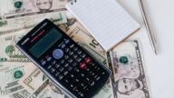 Kalkulator, notatnik i banknoty symbolizujące finanse osobiste i przelewy bankowe
