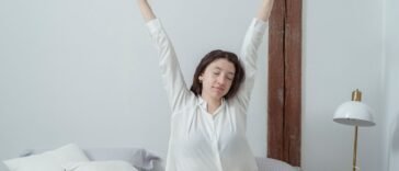 Zmęczona kobieta ziewa i przeciąga się w łóżku po przebudzeniu