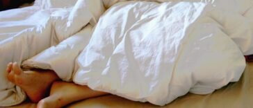 Stopy pod kołdrą w łóżku, gdy w nocy pojawia się skurcz łydki