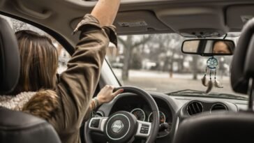 Młoda osoba prowadząca samochód, dłonie na kierownicy