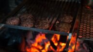 Kotlety burgerowe z mięsa mielonego smażące się na ruszcie grilla