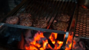 Kotlety burgerowe z mięsa mielonego smażące się na ruszcie grilla