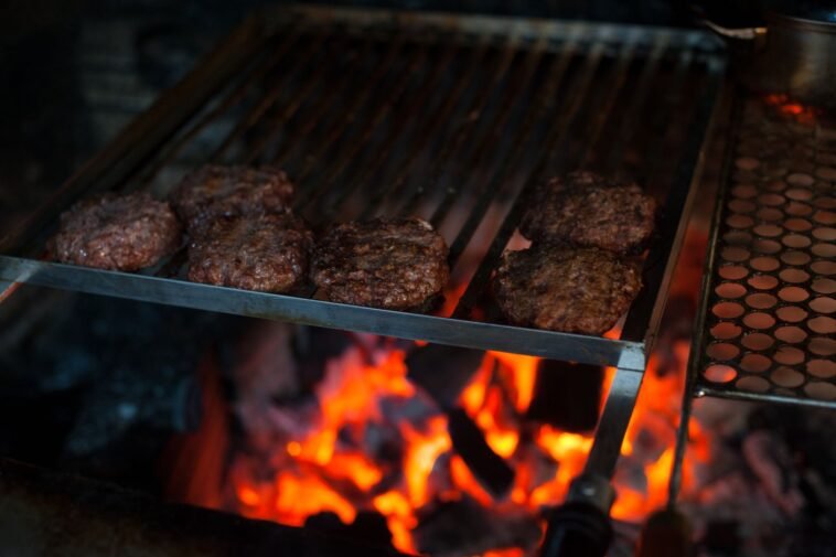 Wystarczy jeden niedosmażony kotlet. Bakteria z mięsa mielonego uderza w nerki tydzień po zatruciu Kotlety burgerowe z mięsa mielonego smażące się na ruszcie grilla