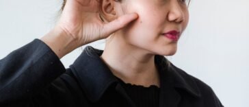 Kobieta przykłada dłoń do ucha, wsłuchując się w dźwięk