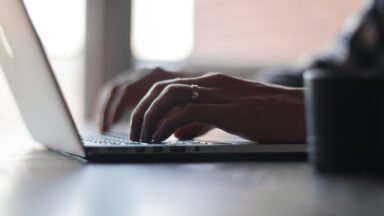 Dłonie piszące na klawiaturze laptopa, praca przy komputerze a ryzyko zespołu cieśni nadgarstka