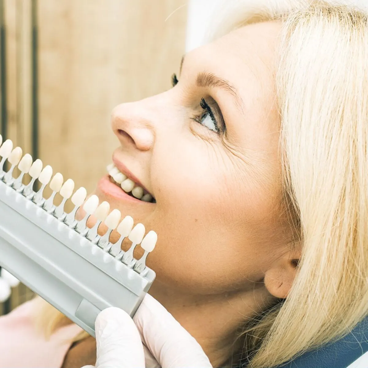 Dentysta dobiera odcień zębów pacjentki za pomocą kolornika przed wybielaniem