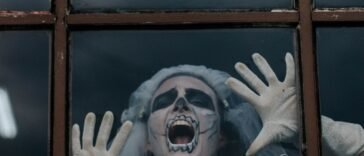 Kobieta w halloweenowym przebraniu krzyczy za szybą