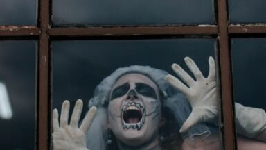 Kobieta w halloweenowym przebraniu krzyczy za szybą