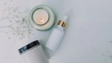 Serum z pipetą i słoiczek kremu do twarzy na jasnym blacie obok świecy