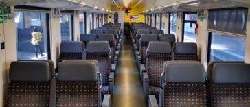 Puste wnętrze wagonu kolejowego z granatowymi fotelami we wzór kolorowych kropek