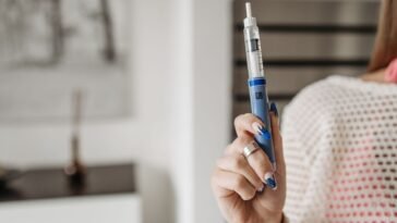 Kobieta trzyma w dłoni pen z lekiem do wstrzykiwań podskórnych