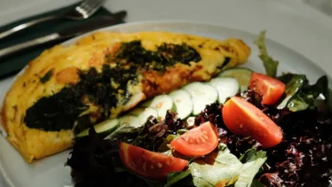 Prosty omlet: przepis z 3 jajek w 8 minut i 4 warianty Prosty omlet z jajek złożony na pół, podany z sałatą i pomidorem