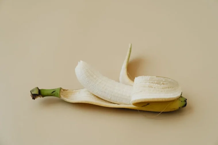 Obrany banan ze skórką na beżowym tle, skórka od banana na zęby
