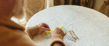Starszy mężczyzna przegląda blistry z tabletkami na cholesterol przy stole