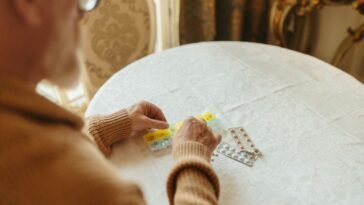 Starszy mężczyzna przegląda blistry z tabletkami na cholesterol przy stole