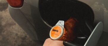 Dłoń trzymająca pistolet dystrybutora podczas tankowania samochodu na stacji paliw