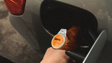 Dłoń trzymająca pistolet dystrybutora podczas tankowania samochodu na stacji paliw