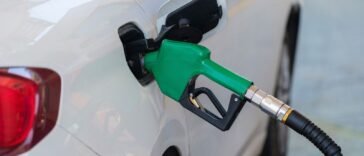 Pistolet dystrybutora we wlewie paliwa białego samochodu podczas tankowania