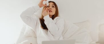 Kobieta zakrapia oko kroplami nawilżającymi, które łagodzą dyskomfort przy pękniętym naczynku