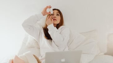 Kobieta zakrapia oko kroplami nawilżającymi, które łagodzą dyskomfort przy pękniętym naczynku