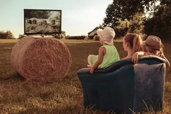 Dzieci, oglądające telewizję w szczerym polu. 